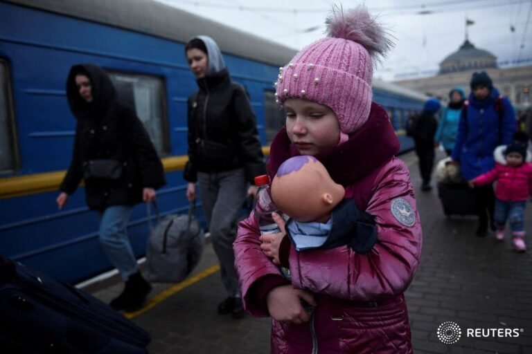 A girl holds a doll as civilians fleeing Russia’s invasion of Ukraine board a tr