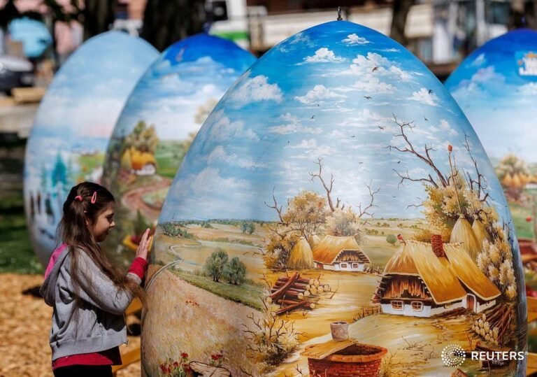 A girl looks at two-meter-high Easter eggs painted in the traditional naive art