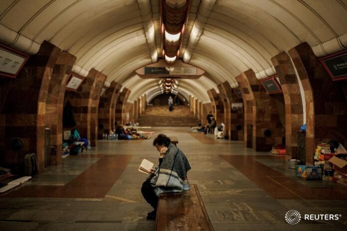 A woman reads a book while sheltering from Russian shelling in a metro station i