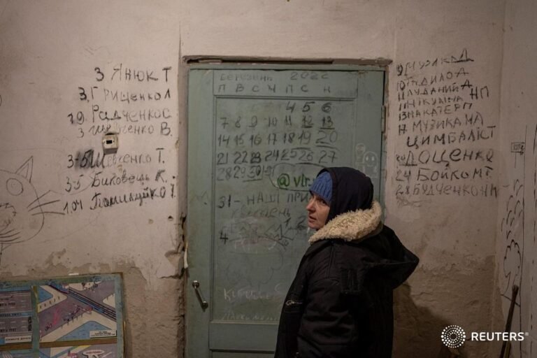 Halyna Tolochina stands in front of a wall inscribed with the names of people wh