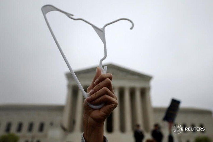 A demonstrator holds up a clothes hanger during a protest outside the U.S. Supre