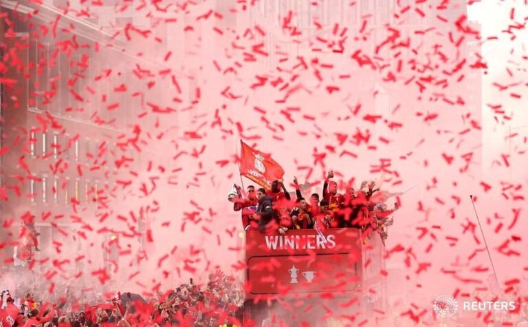 Confetti and red smoke shroud Liverpool players as they celebrate on board an op