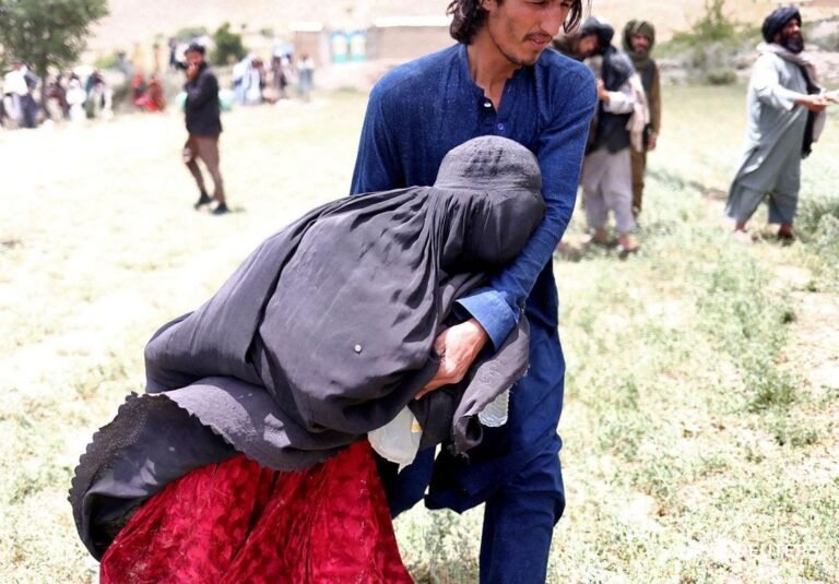 An Afghan woman is helped to reach an evacuation helicopter after she lost some