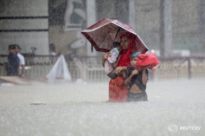 People wade through the water as they look for shelter during a flood caused by 