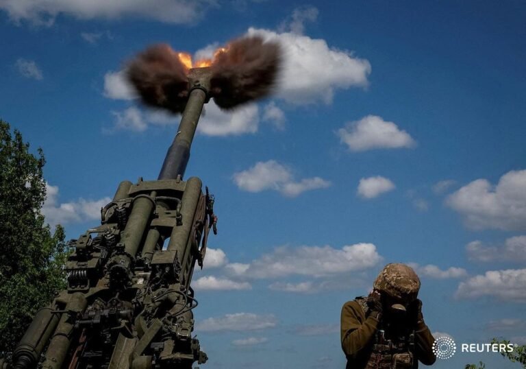 Ukrainian service members fire a shell from a M777 Howitzer near a front line in